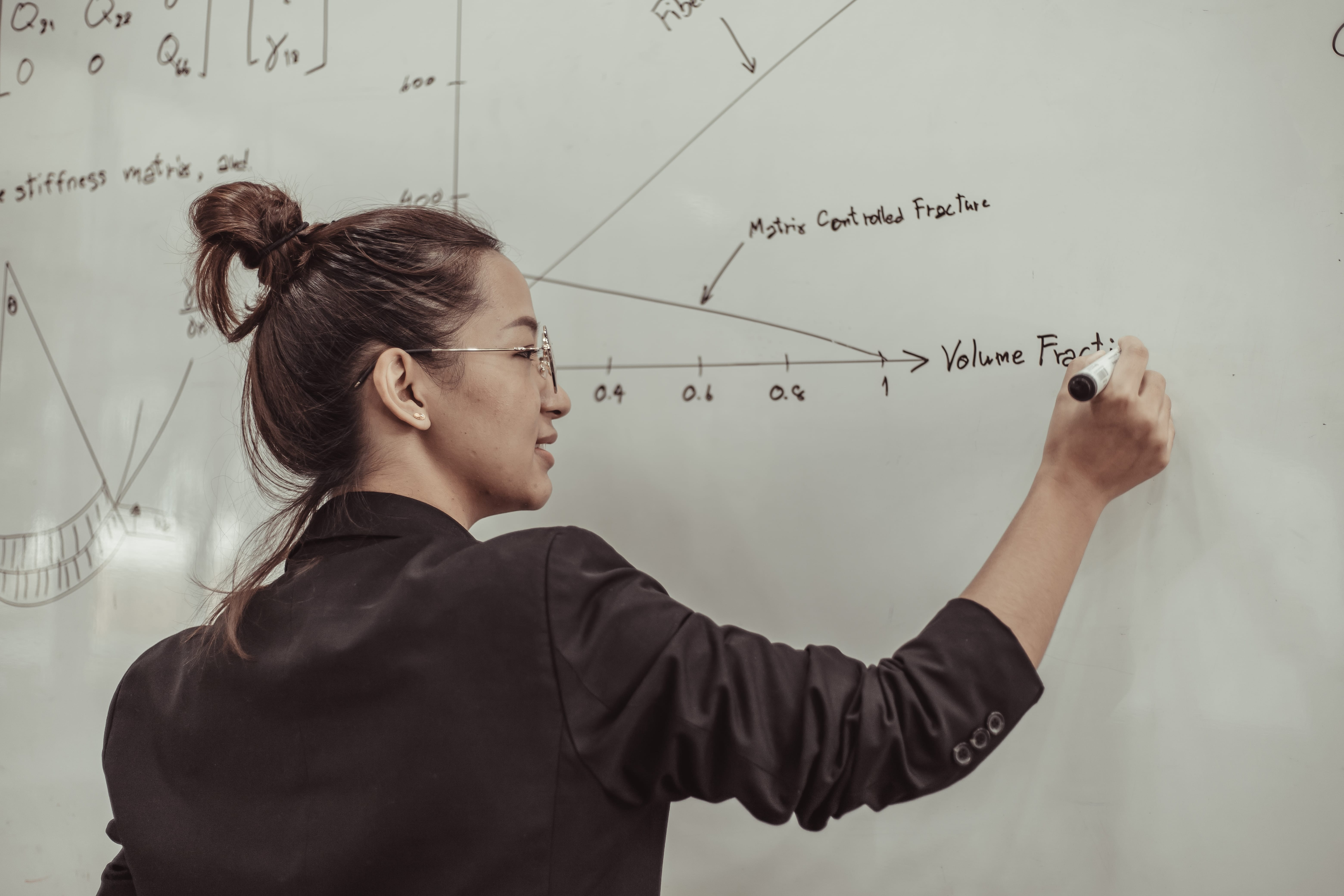 Person writing math notation on a whiteboard